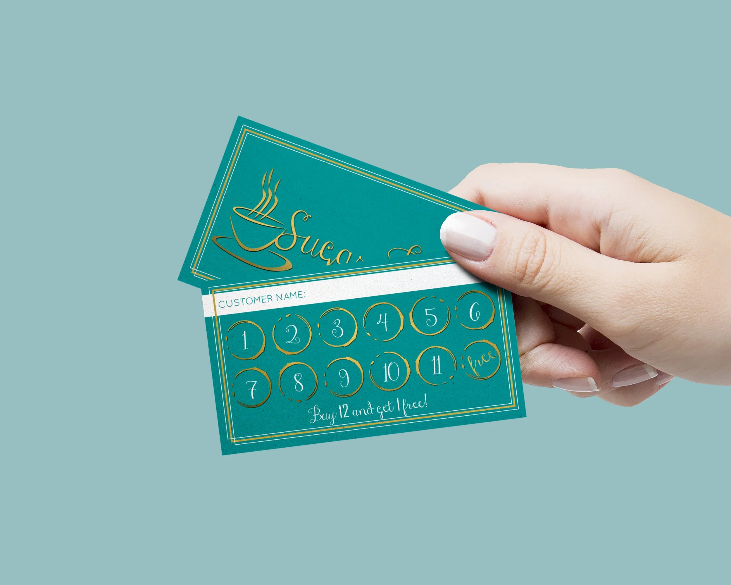 Close-up of a person's hand holding a teal-colored scratch-off card with numbered circles and text advertisements, with a light blue background.