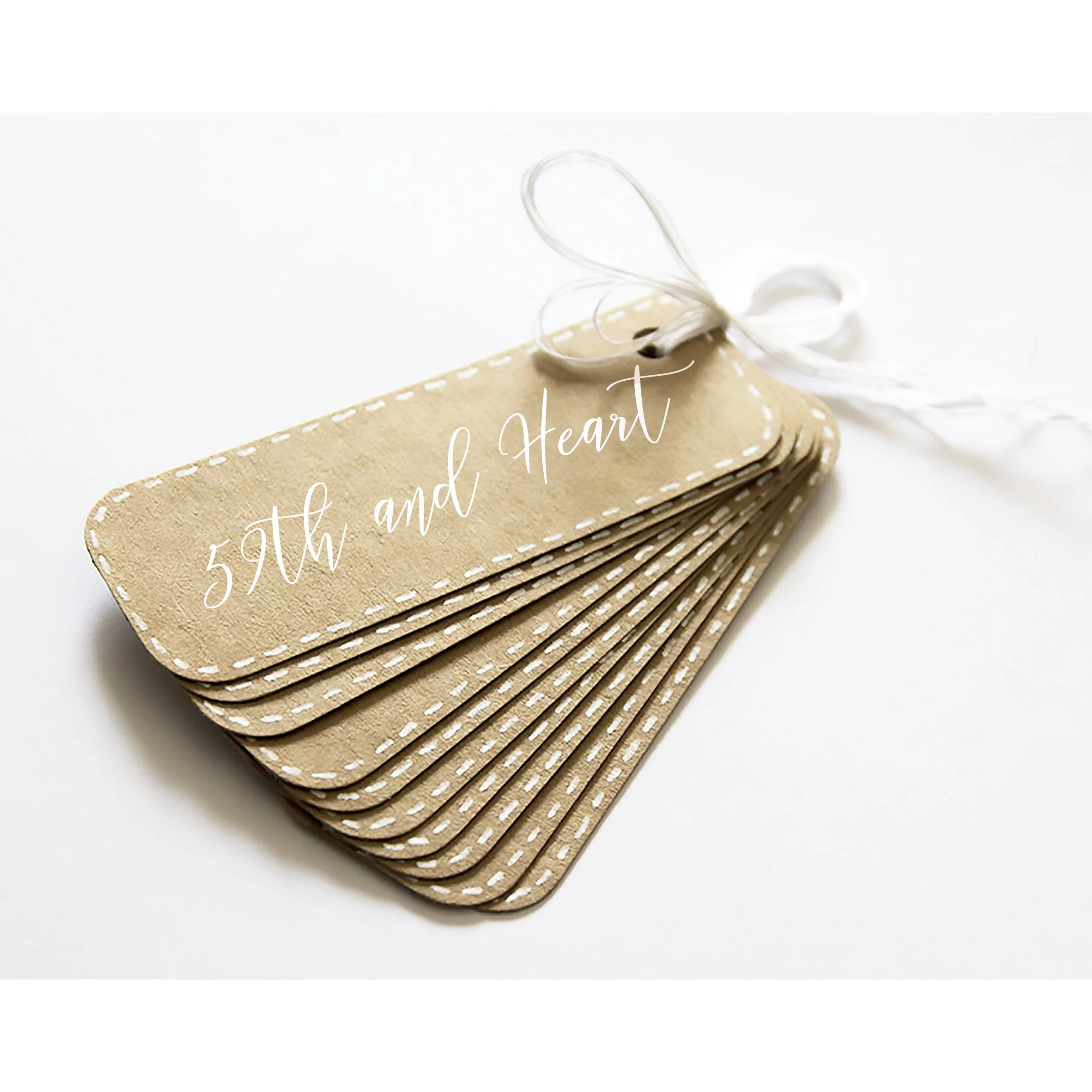 A stack of beige felt tags with white dashed stitching along the edges, tied with a white ribbon, against a white background.