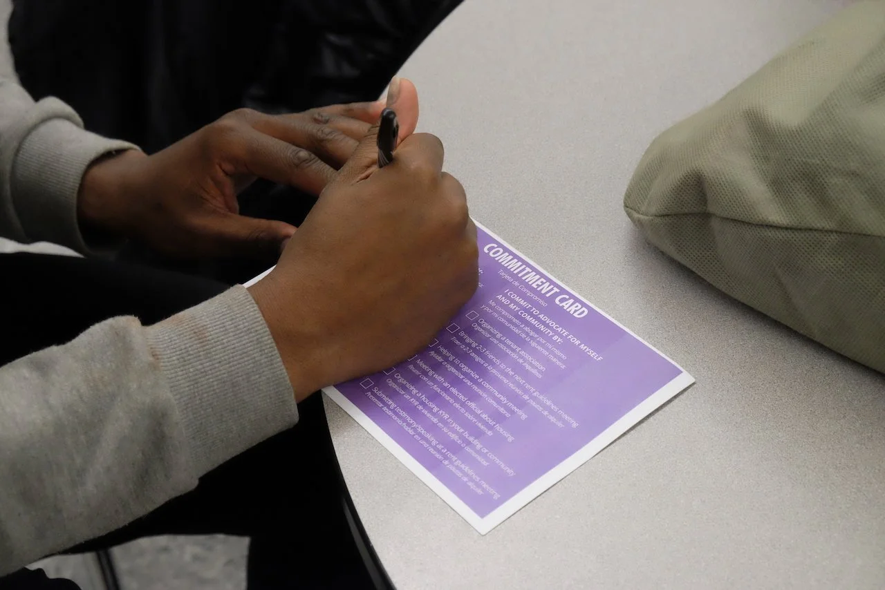 Close up of hands filling out a purple commitment card at a table.