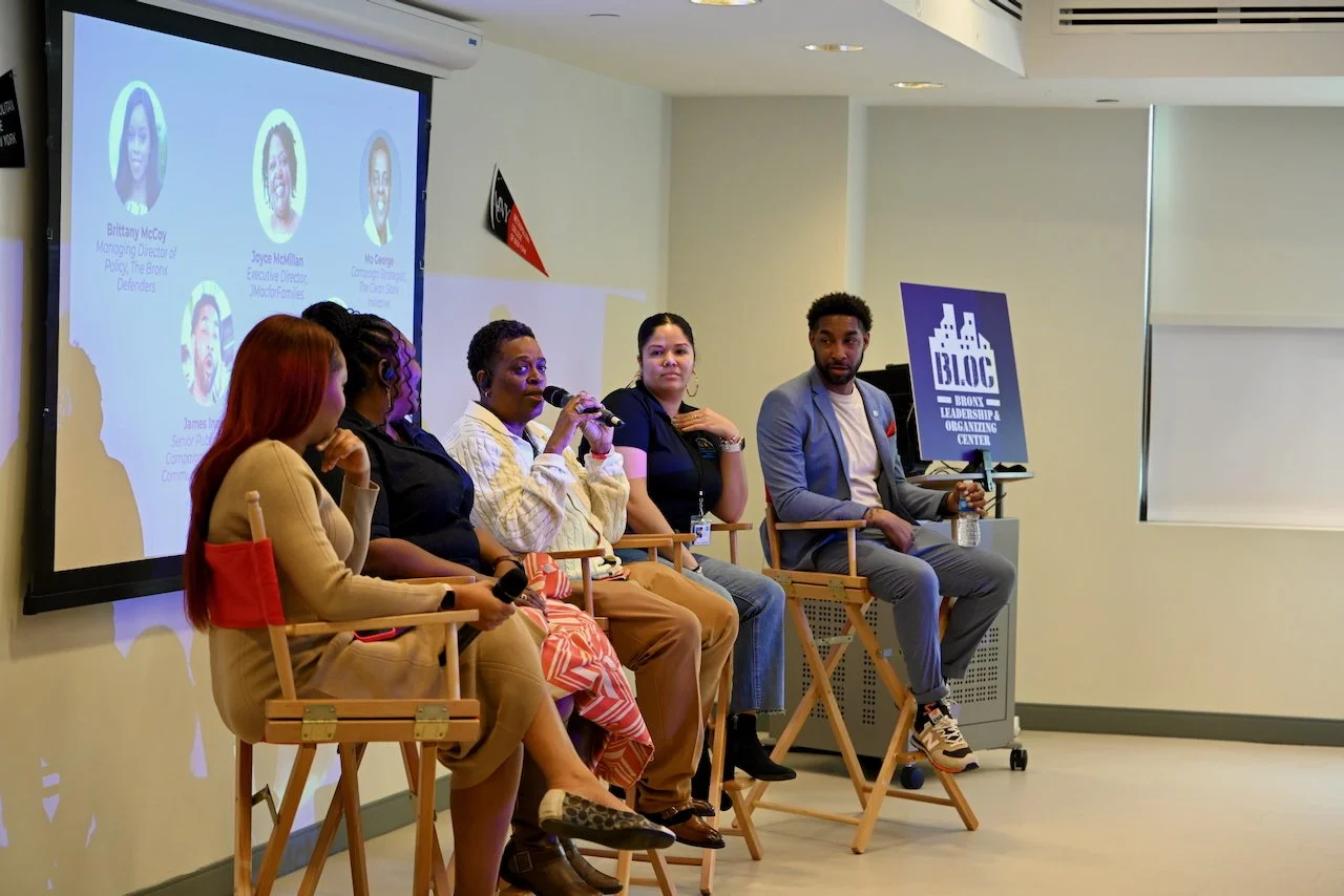 Panel discussion with five diverse women and one man seated on stage at Metropolitan College of the Bronx, with a large screen showing their names and titles in the background.