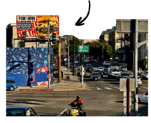 Urban street scene with traffic, pedestrians, a large billboard, graffiti-covered wall, and a street sign indicating the direction to Fwy North.