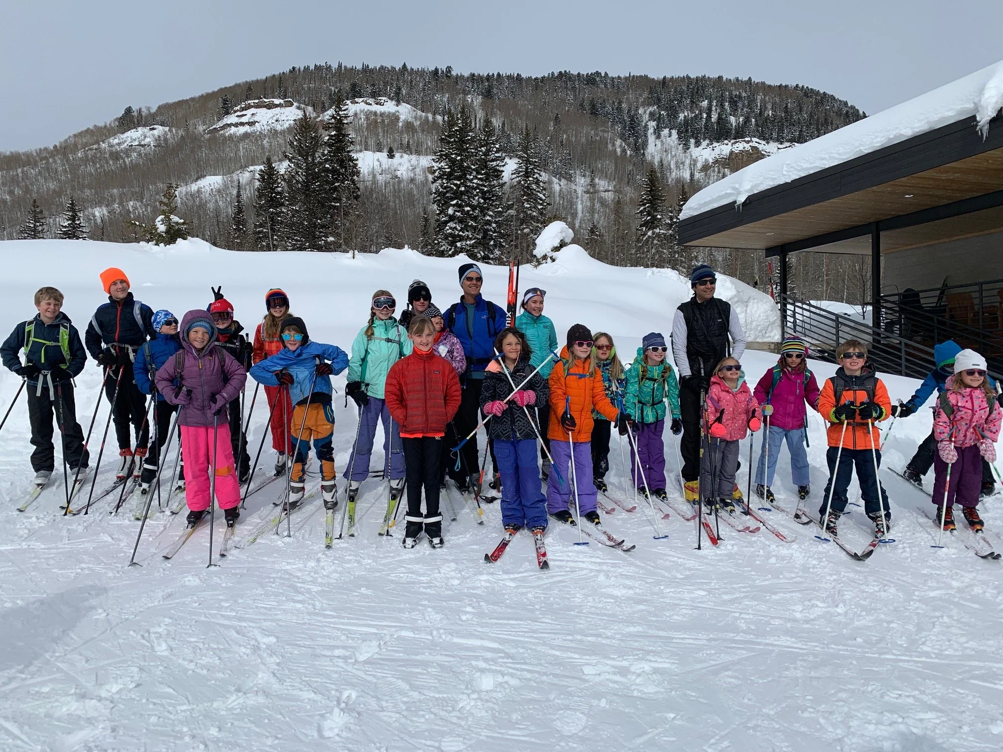 Group of young skiers in a row with a mountain backdrop.