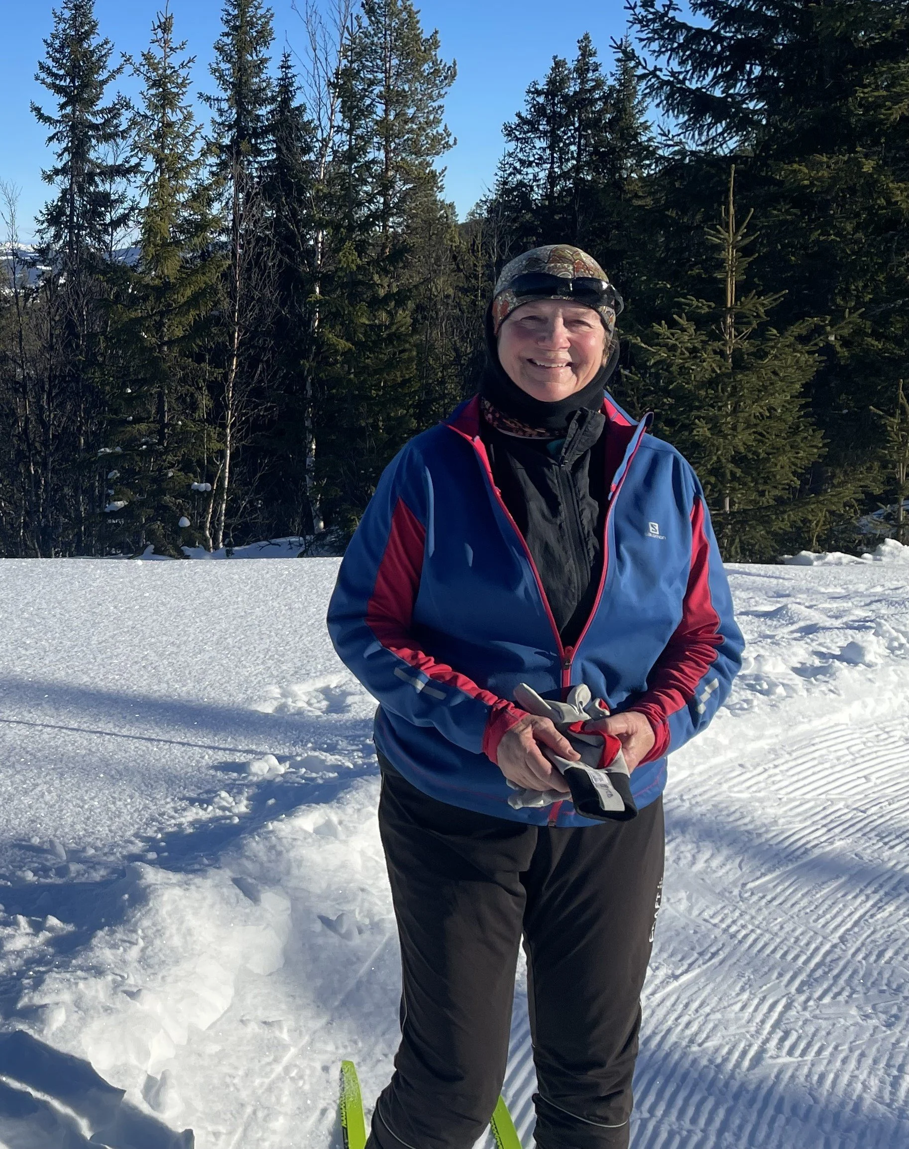 A woman with short curly hair smiling, wearing a red top.
