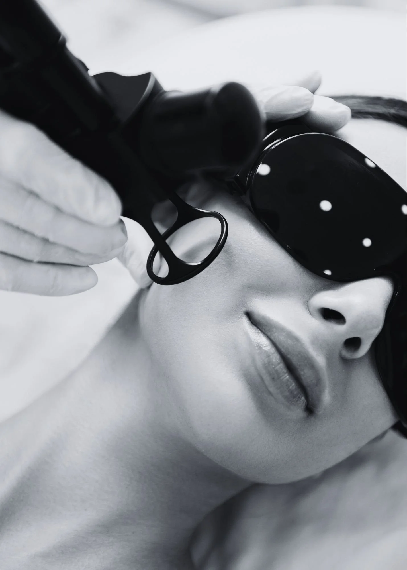 A woman receiving a facial treatment with a steam machine in a spa or clinic setting.