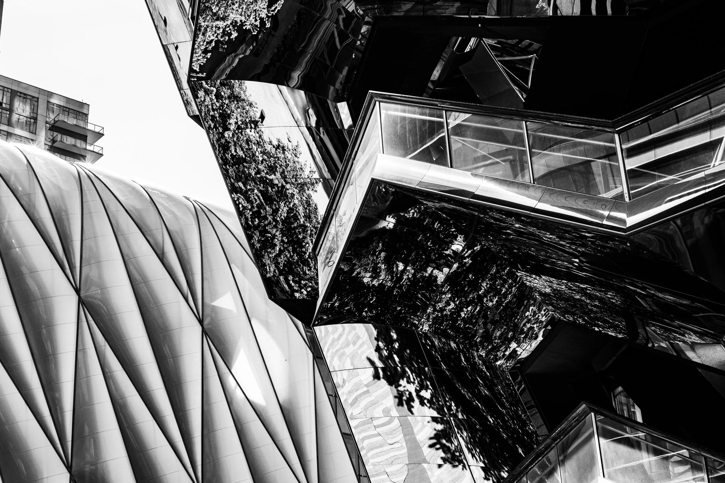 Black and white photo of modern buildings with reflective glass surfaces and curved architectural design.