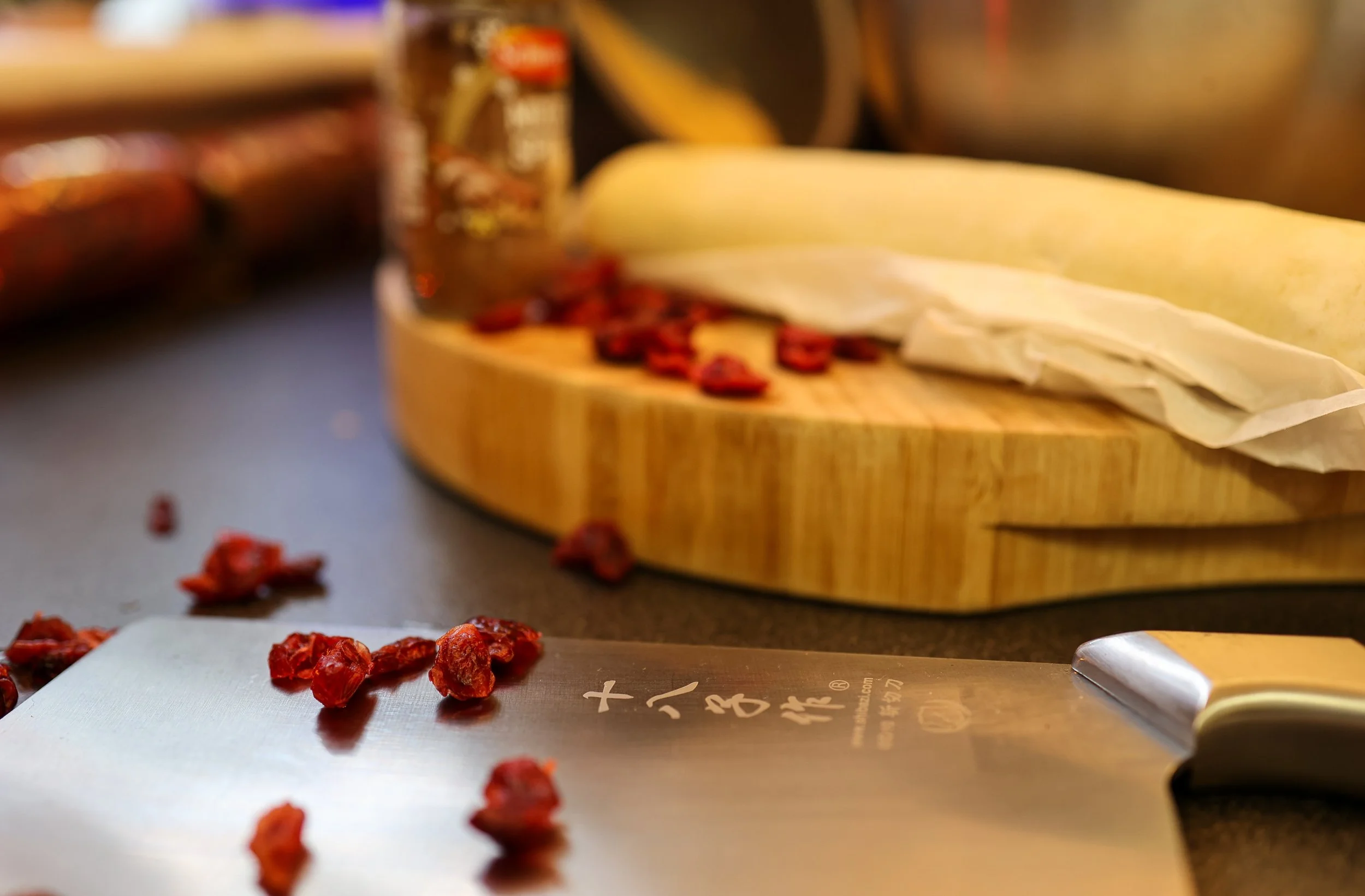 Chopped dried red berries on a cutting board with a cleaver and a rolling pin in the background.