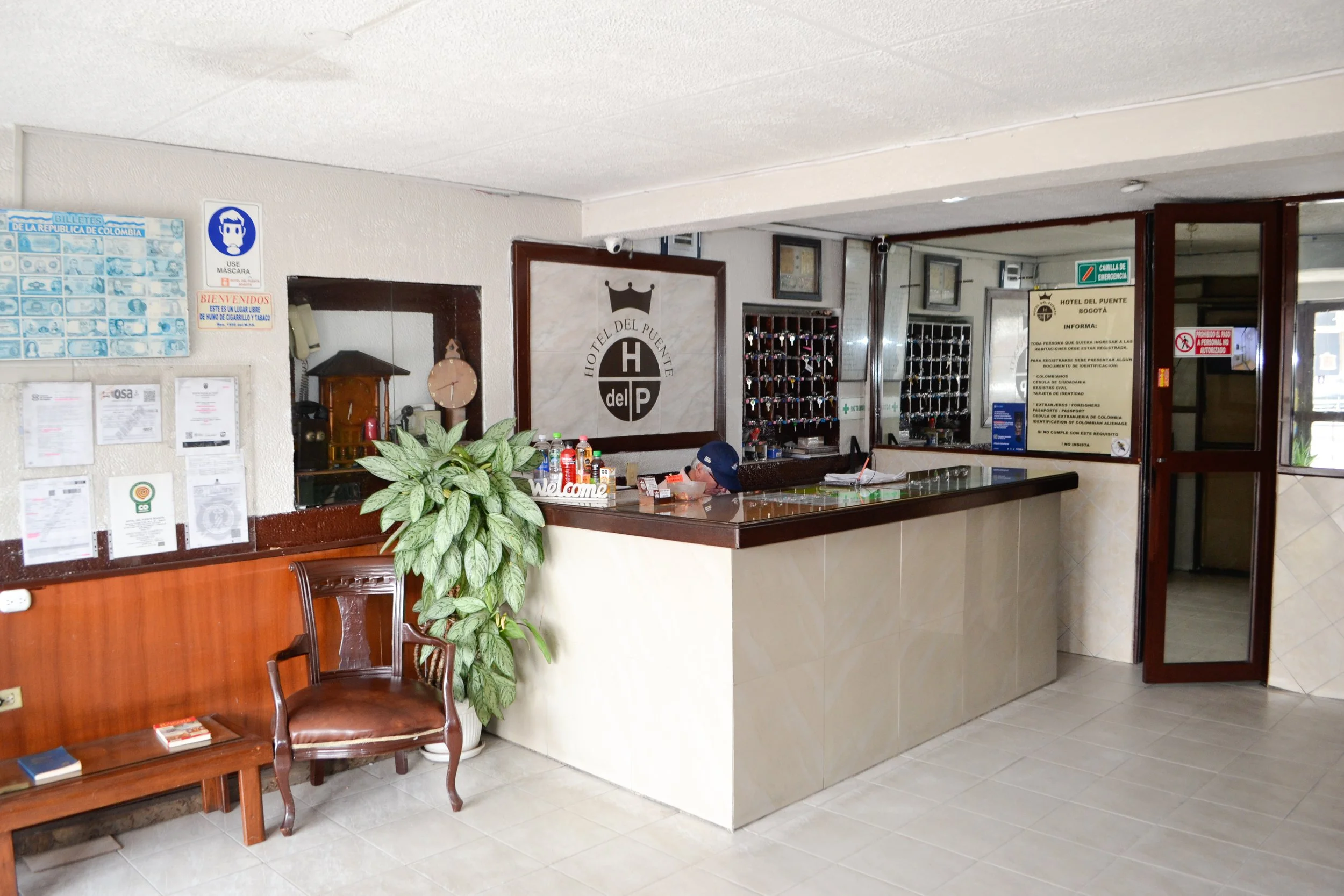 Recepción del hotel con señalización y llaves del armario de llaves en el fondo.