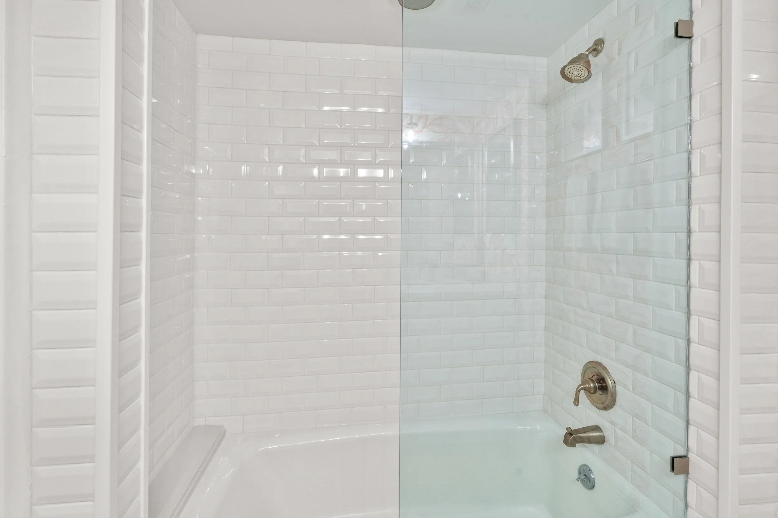 Bathroom shower with white subway tiles, a glass door, and brushed nickel fixtures.