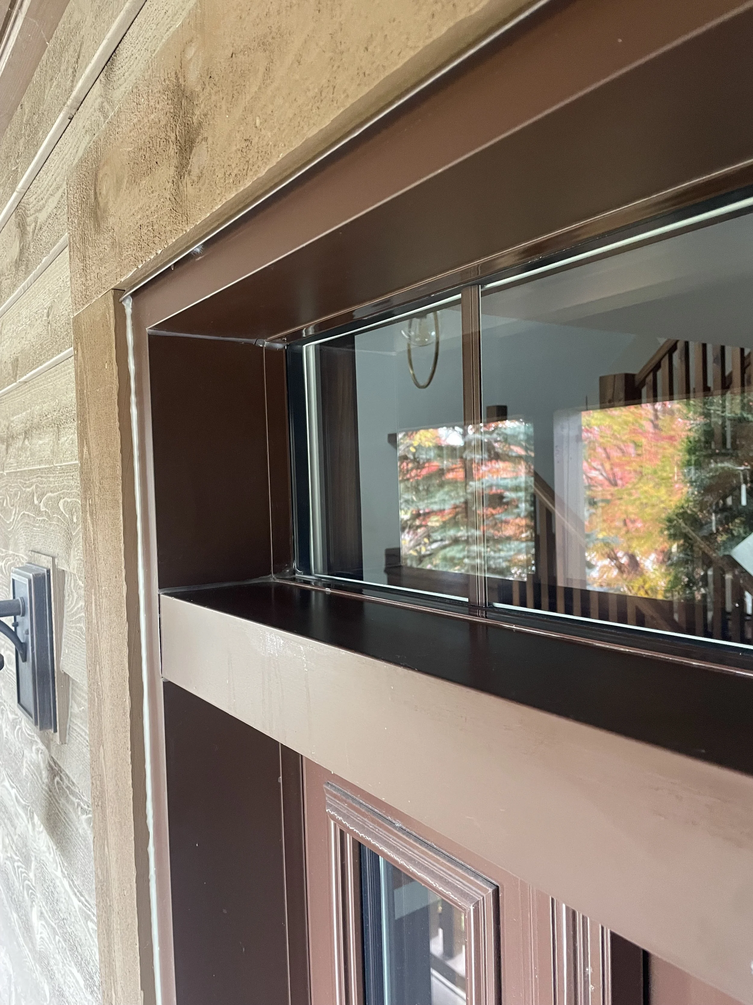 Fenêtre à guillotine dans une maison avec un cadre en bois brun et un mur en pierre à côté.