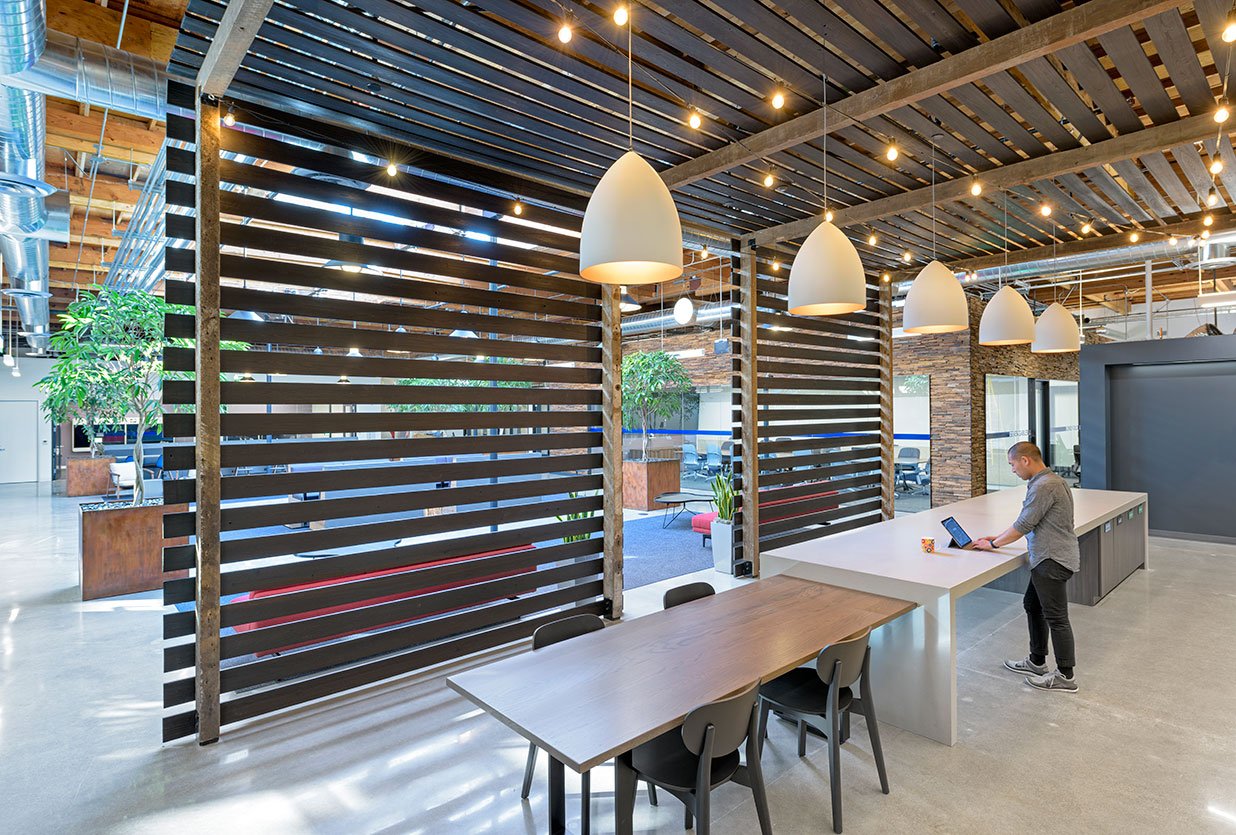 Interior view of LinkedIn office featuring wooden slat partitions, collaborative workspaces, pendant lighting, and structural engineering by PARADIGM.