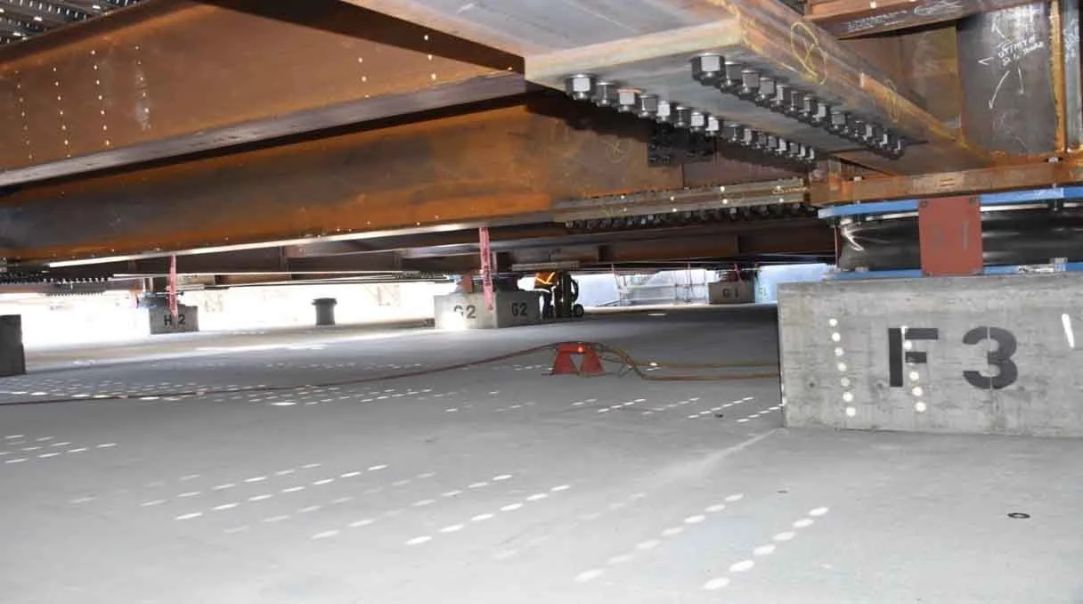 Underground parking garage with concrete foundations and painted parking spots, supports, and equipment.