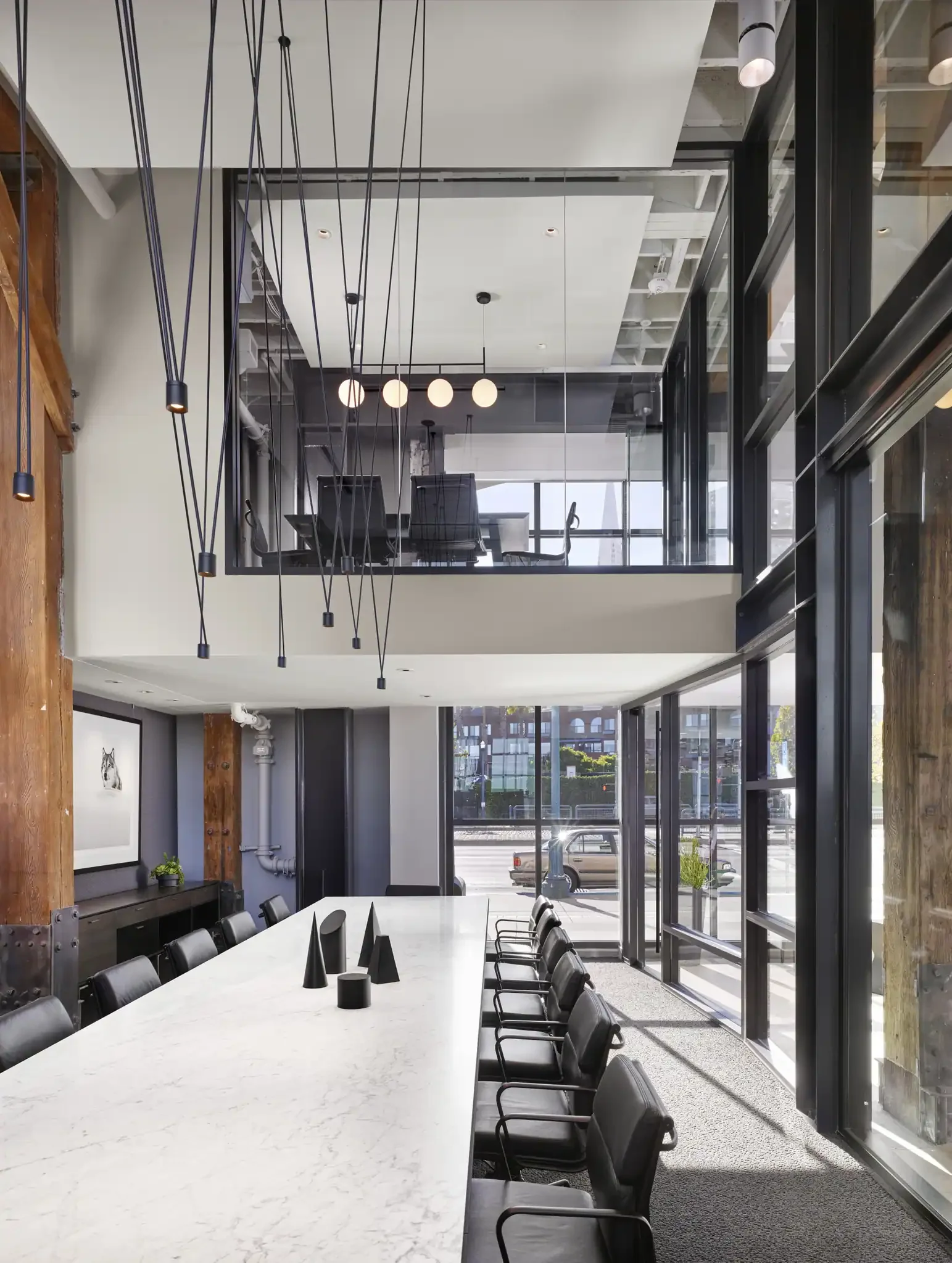 Interior conference room view of the PARADIGM Structural Engineers 8VC office featuring a long conference table, pendant lighting, and an elevated glass-enclosed meeting room above.