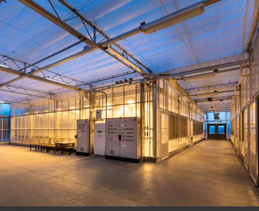 Interior corridor view of the PARADIGM Structural Engineers Bayer CropScience greenhouse facility featuring structural steel framing, translucent walls, and control panels.