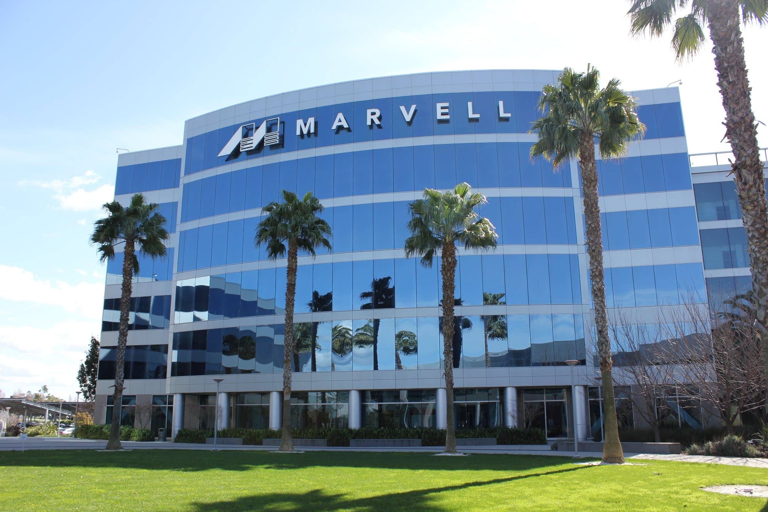 Daytime exterior view of the PARADIGM Structural Engineers Marvell corporate office building featuring a glass facade, corporate signage, and surrounding palm trees.