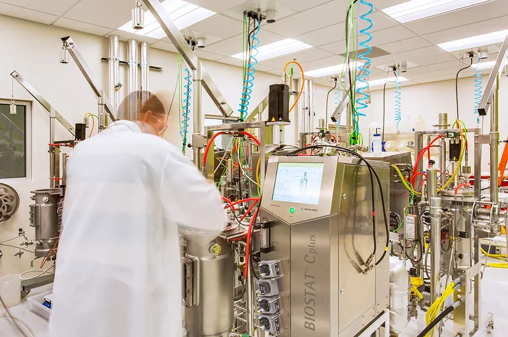 Researcher in a lab coat operating laboratory equipment at the Bayer CropScience facility in West Sacramento.