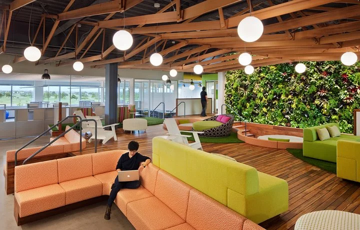 Interior office lounge designed for PARADIGM Structural Engineers featuring modern seating, a living green wall, exposed wooden roof trusses, and globe pendant lighting.
