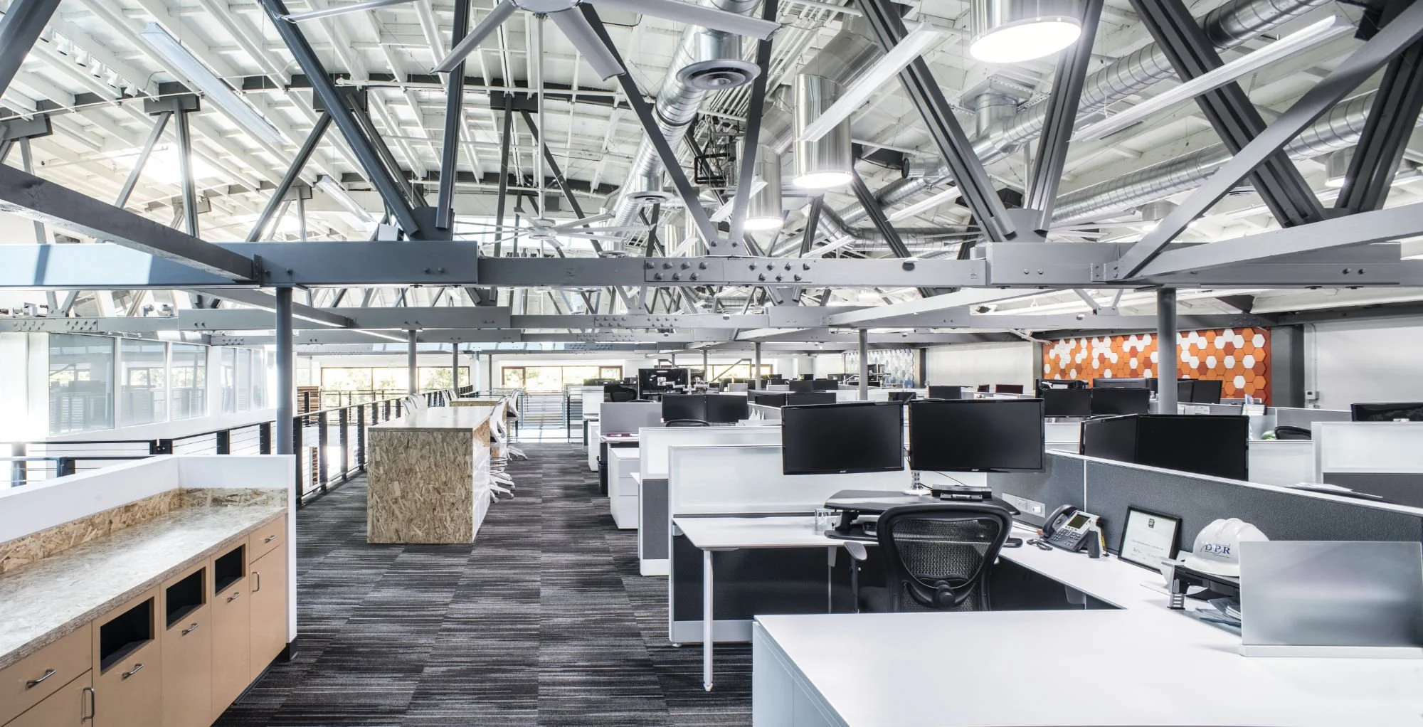 Interior open office layout of the PARADIGM Structural Engineers DPR SF Office featuring modern work cubicles, computer desks, and exposed structural steel ceiling framing.