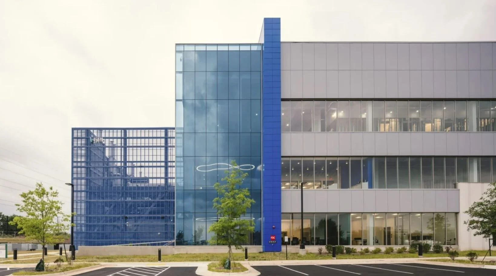 Exterior daytime view of the PARADIGM Structural Engineers Vantage VA13 data center featuring a modern multi-story facade with expansive glass curtain walls and blue structural accents.