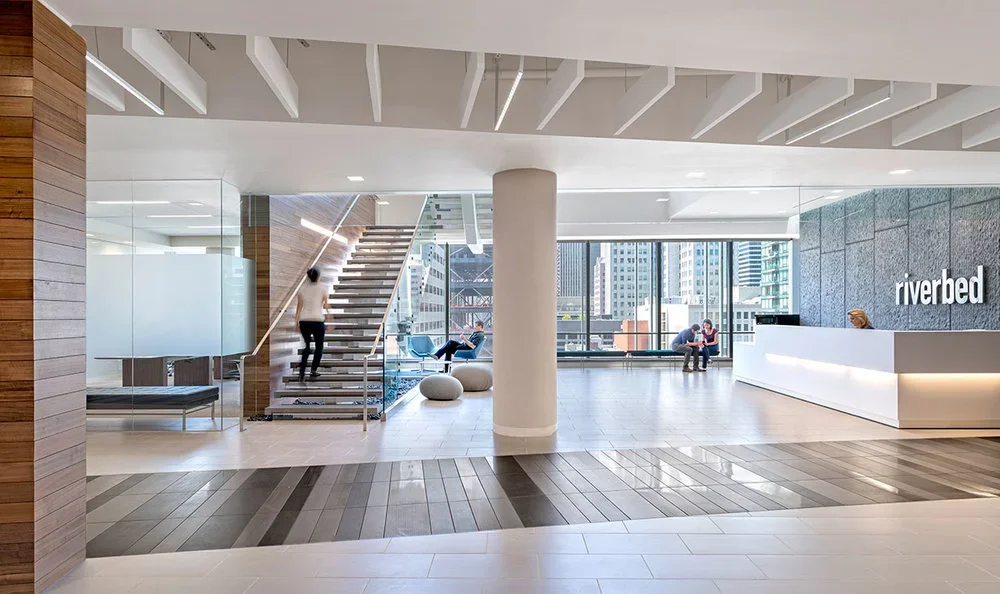 Riverbed Technology office lobby in San Francisco featuring a reception desk, open staircase, and structural design by PARADIGM.