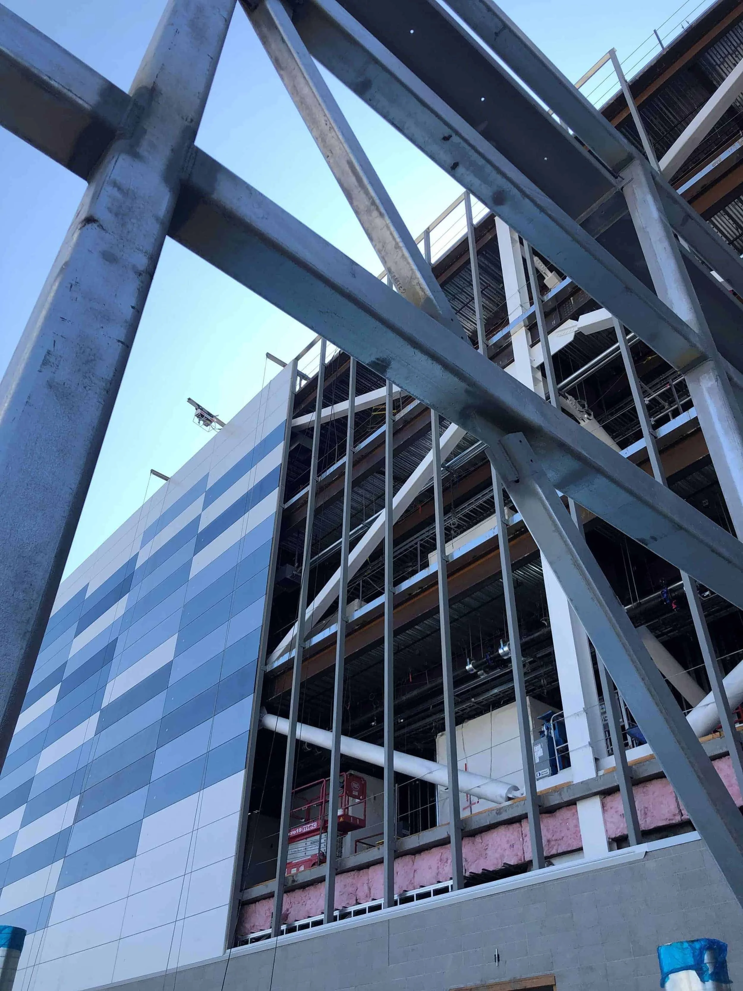 View of a modern building under construction with steel framework and insulation, captured from a low angle with blue sky in the background.