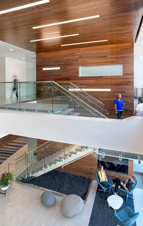 Multi-level interior view of the Riverbed Technology office featuring wooden accent walls, glass stair railings, and a seating area.