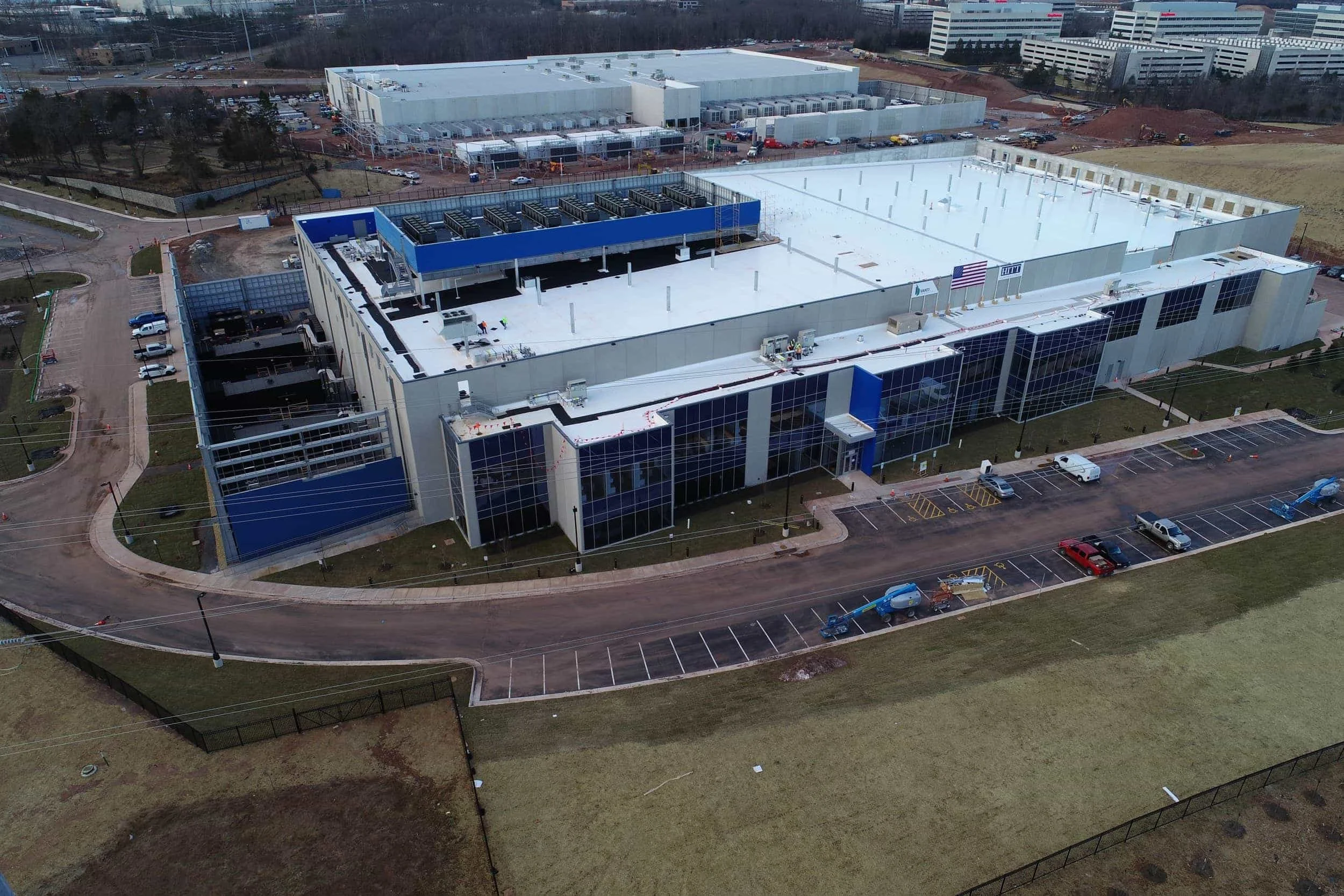 Aerial overview of the PARADIGM Structural Engineers Vantage VA11 data center complex showing extensive facility rooftops, glass-fronted offices, and surrounding parking areas.
