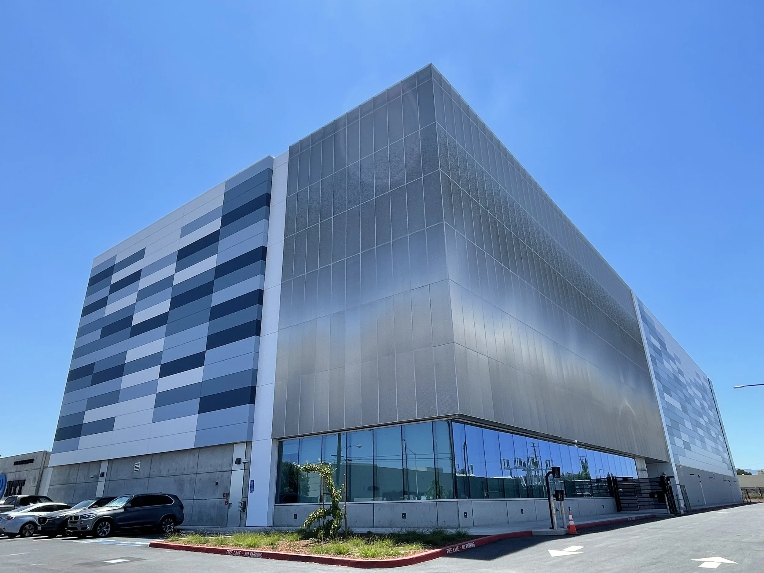 Exterior architectural view of the PARADIGM Structural Engineers NTT SV1 data center showcasing its multi-story facade, perforated metal screening, and ground-level glazing.