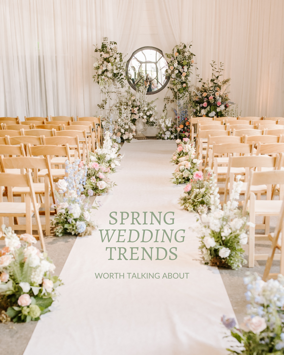 Wedding aisle decorated with floral arrangements, leading to a floral arch with a mirror in the background and soft lighting.