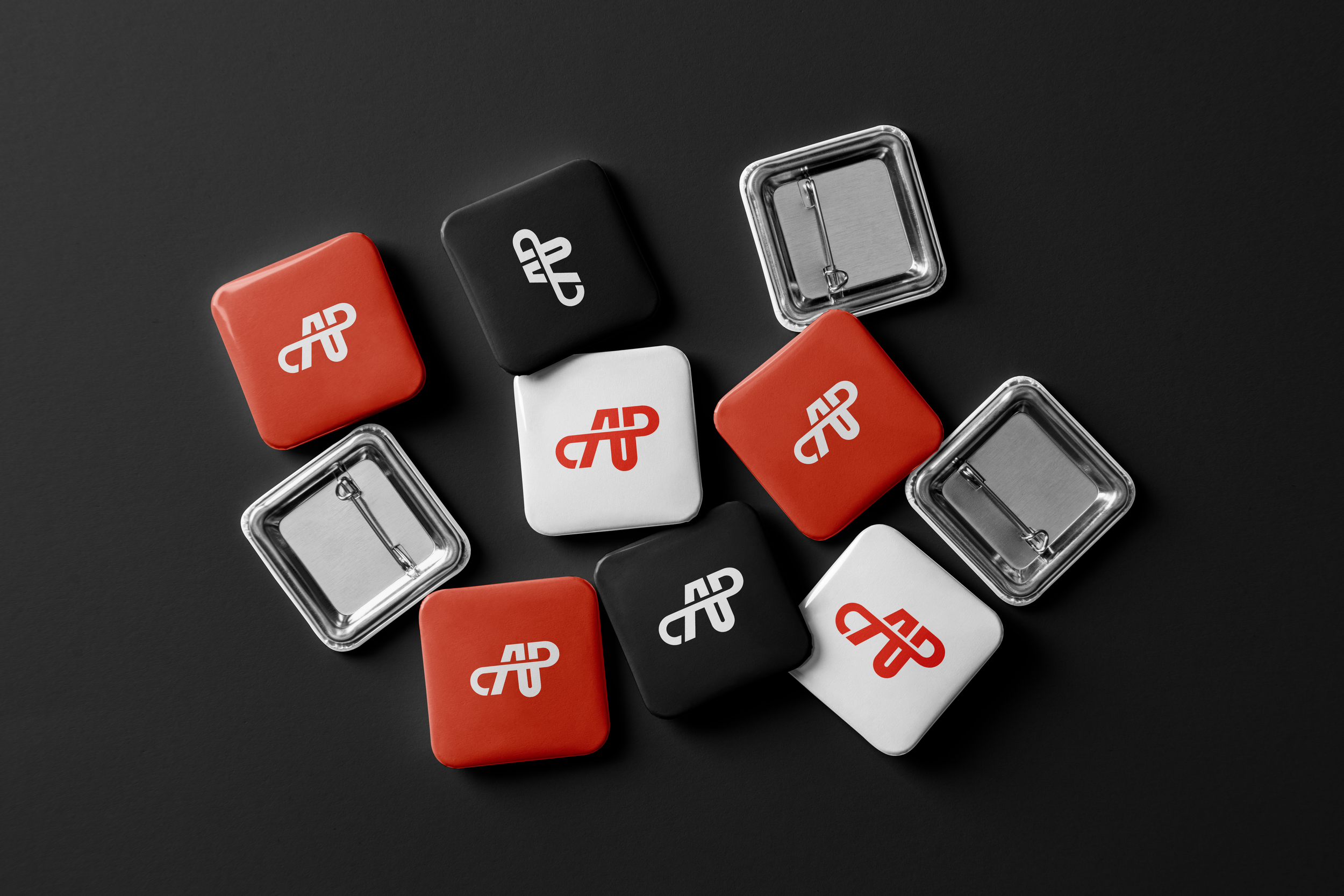 A collection of small, square, plastic cases with clip clasps, some in red, black, and white, featuring a white logo with stylized letters 'AP' on the covers, set against a dark background.