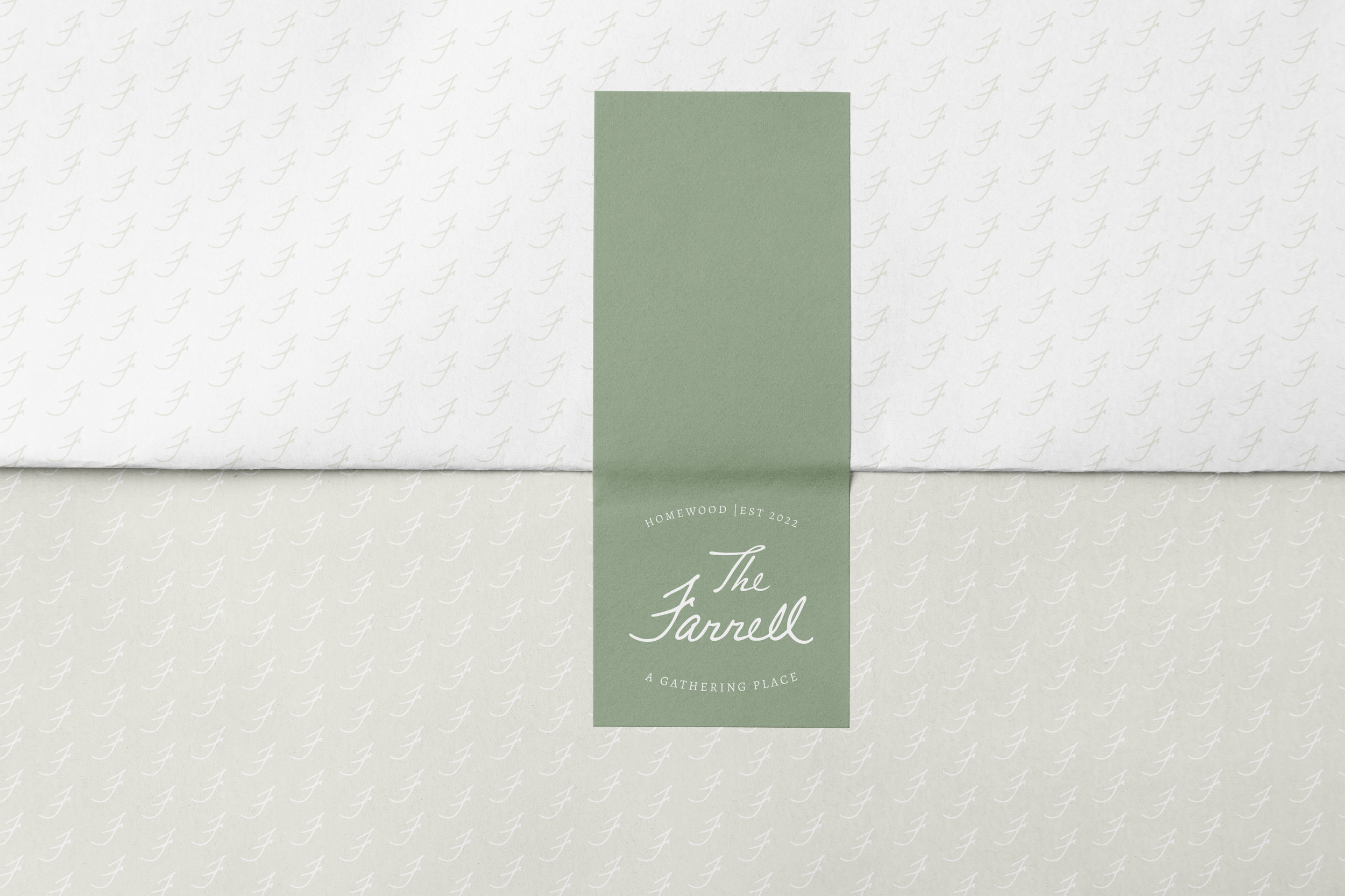 A patterned white paper with a green vertical band in the center that reads 'The Farrell' and 'A Gathering Place' with smaller text above 'HOMEWOOD EST 2022.'