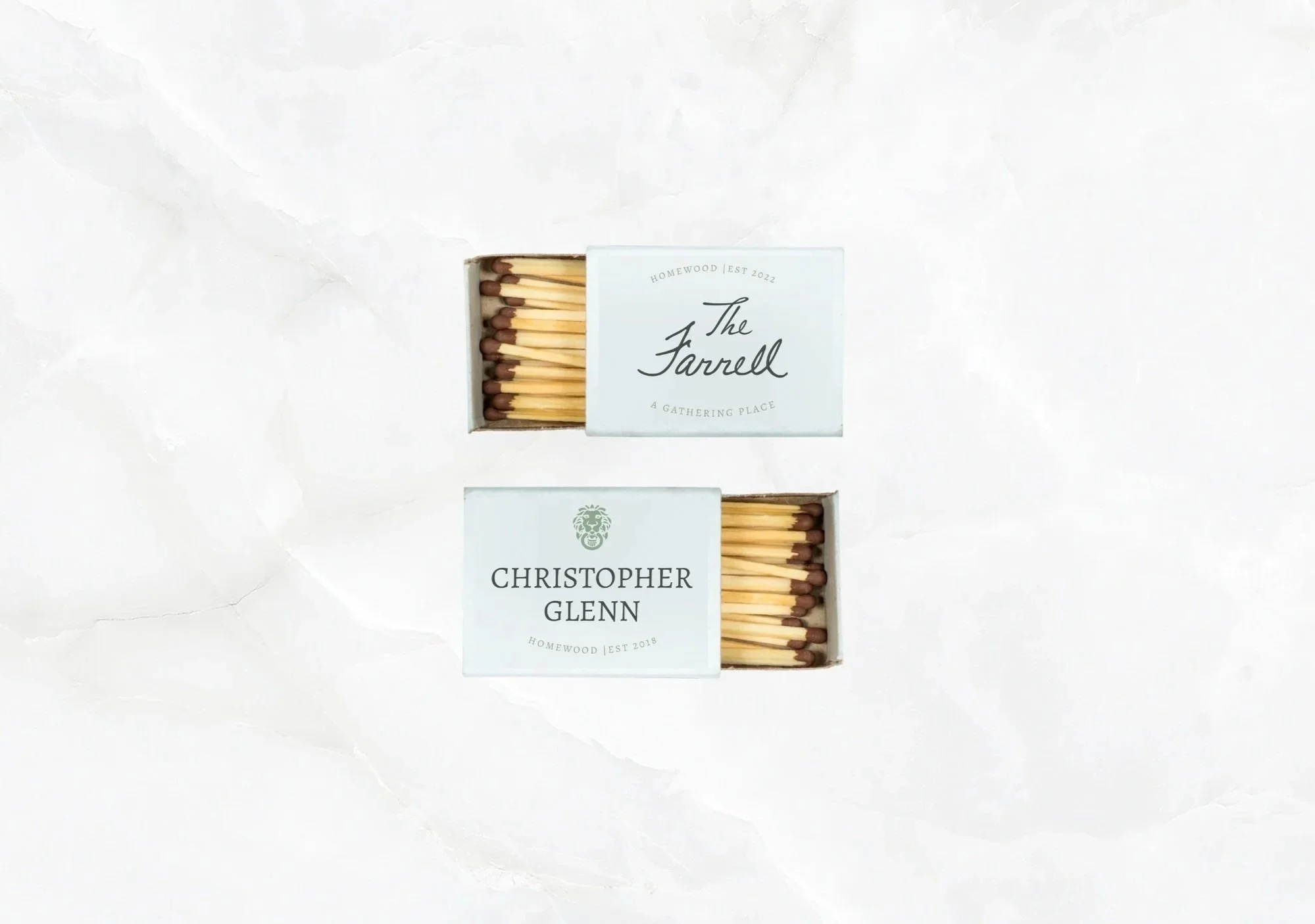 Two matchboxes with filled matches inside, one labeled "The Farrell" and the other labeled "Christopher Glenn.""