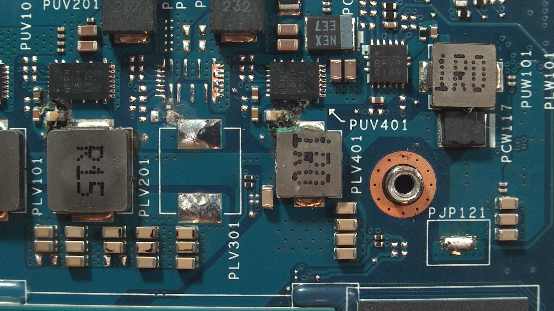 Close-up view of a computer motherboard with various electronic components, including chips, resistors, capacitors, and a circular mounting hole.