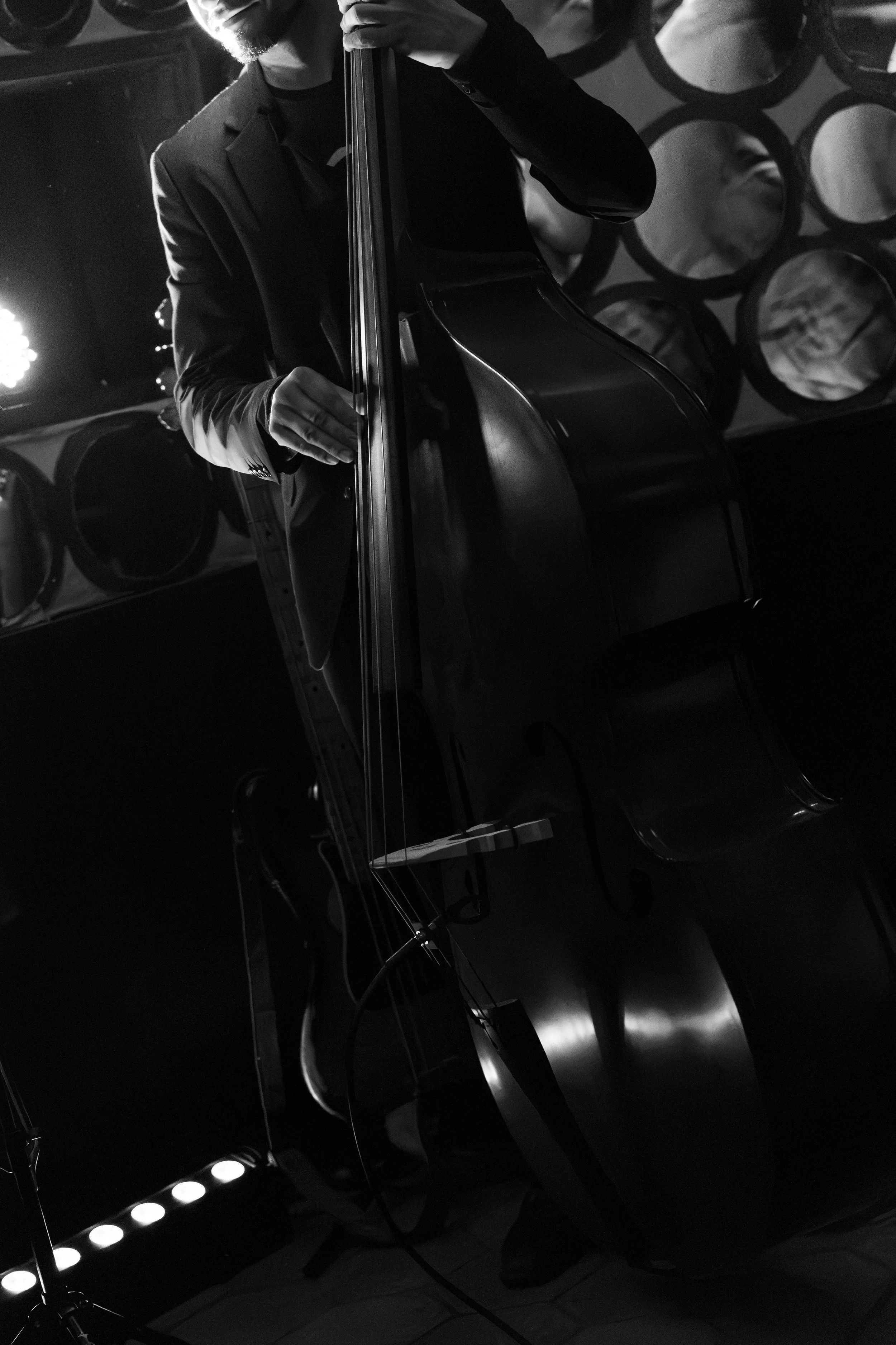 A person playing a grand piano, photographed in black and white, with stage lighting and circular decorations in the background.