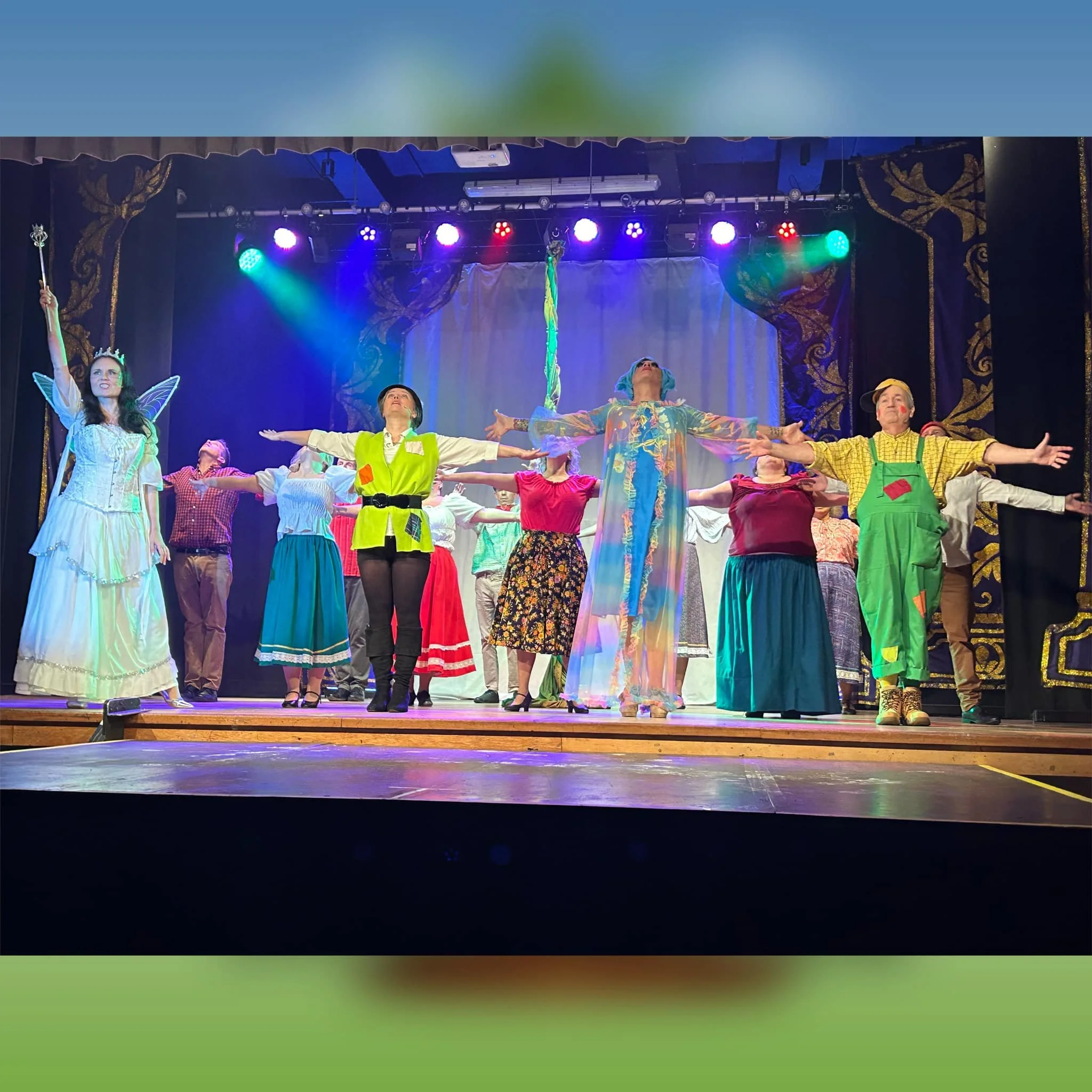 Group of performers on stage dressed in colorful costumes, bowing with arms outstretched after a theatrical performance.
