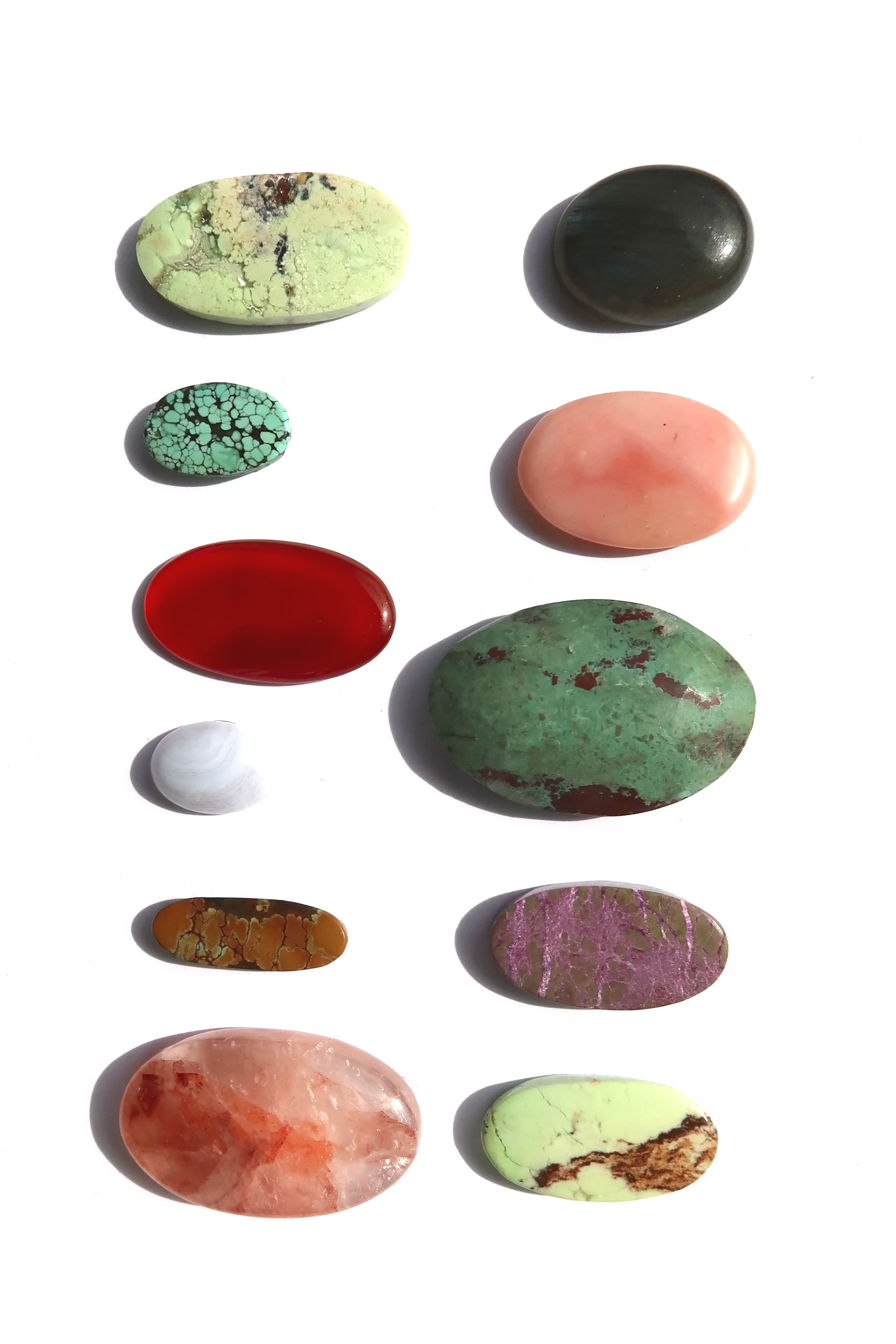 A collection of colorful and patterned polished stones arranged on a white background.
