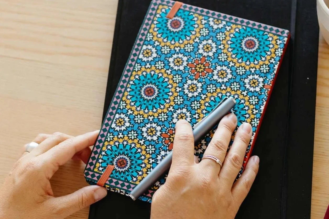 Zwei Hände liegen auf einem guten Notizbuch.