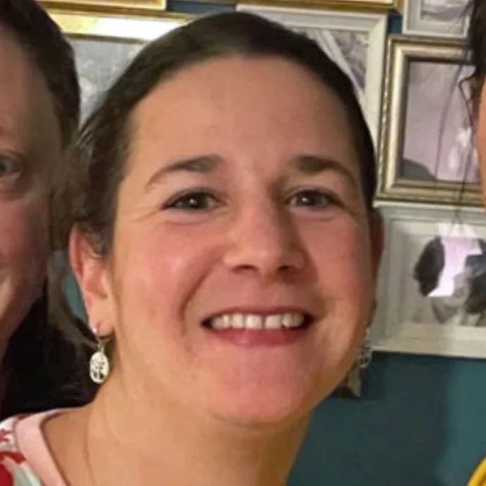 Frau mit rotem Pulli und Ohrringen lacht in die Kamera