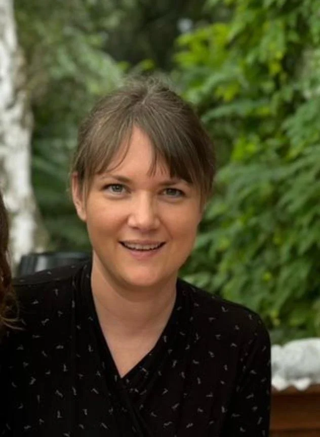 Eine Frau mit dunkler Bluse schaut freundliche in die Kamera.