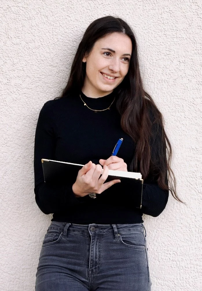 Expertin Heike Störr Copywriting lächelt verträumt und schreibt in ein Notizbuch.