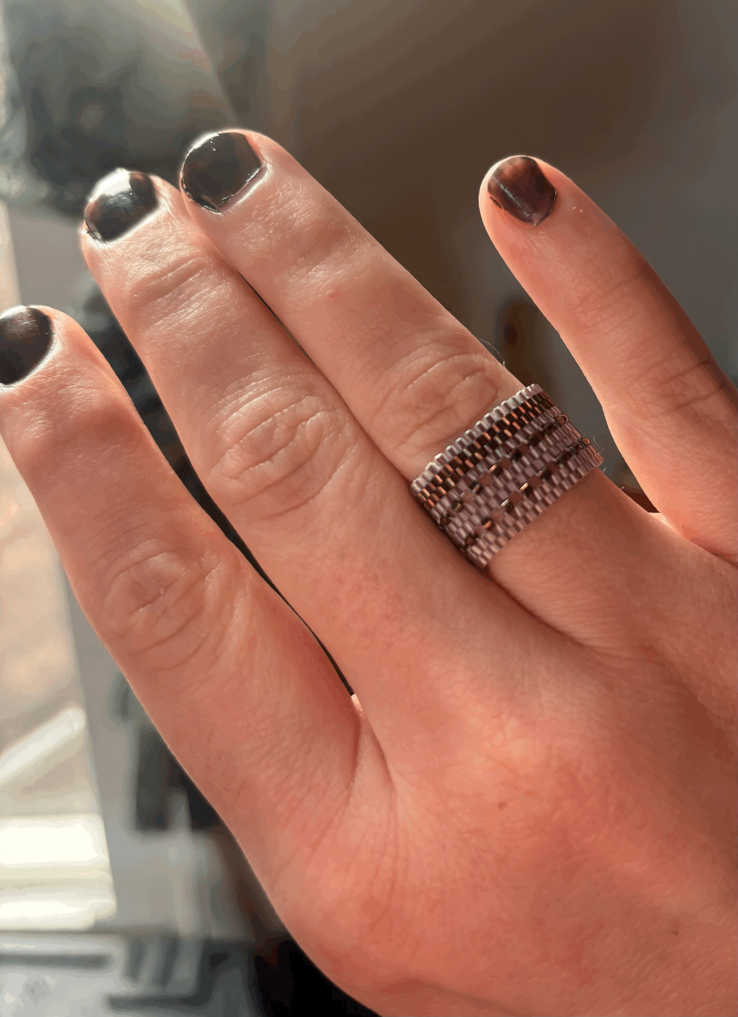 A hand wearing the Lavender bronze iris double latticed ring