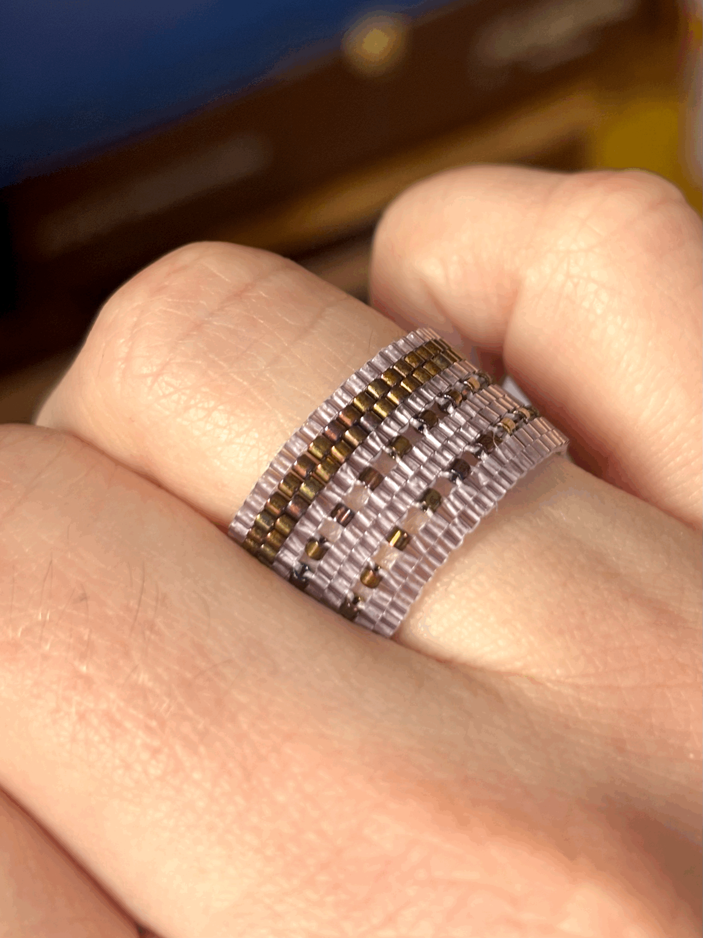 Close-up of a hand wearing the Lavender bronze iris double latticed ring