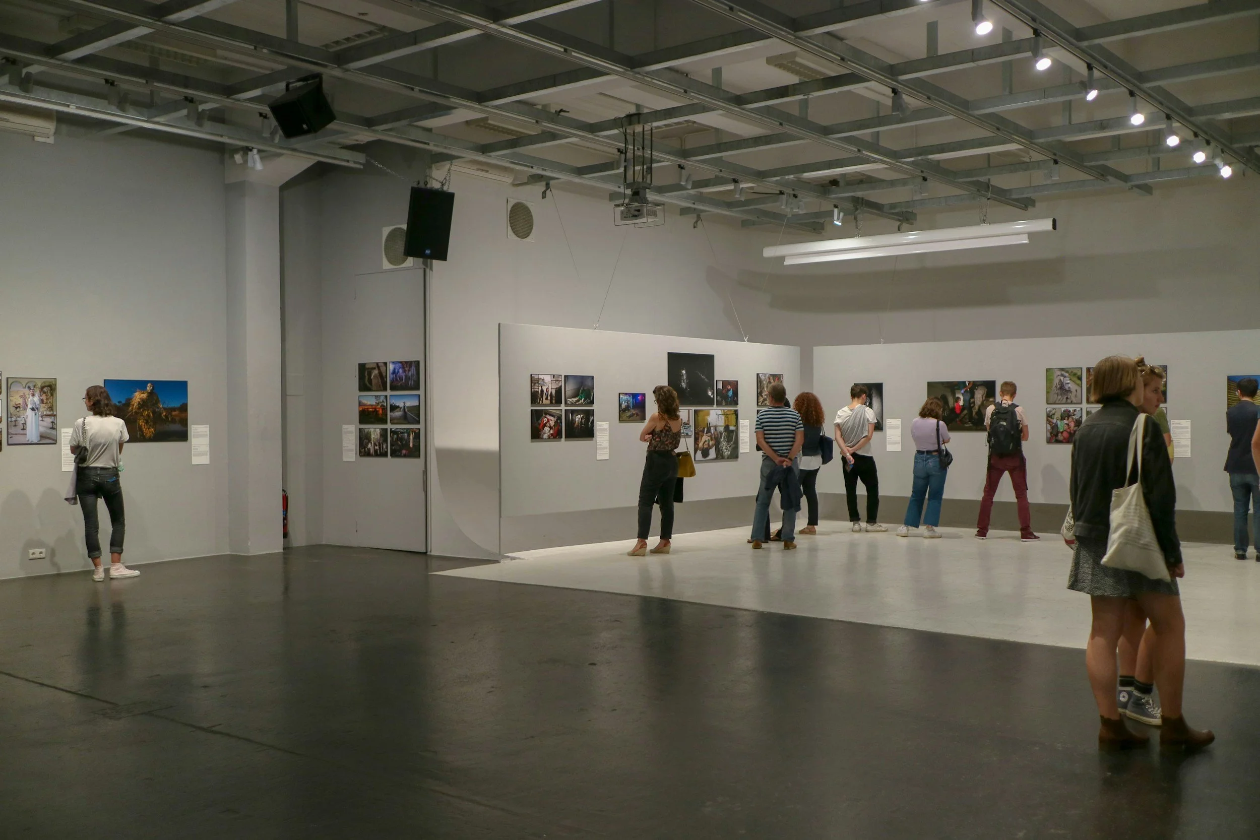 Image of art show in gallery with people looking and enjoying the colorful and powerful artwork