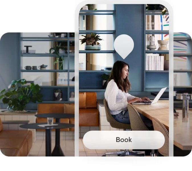 A woman working on a laptop at a wooden table in a modern, cozy cafe with blue shelves and various decorative items.
