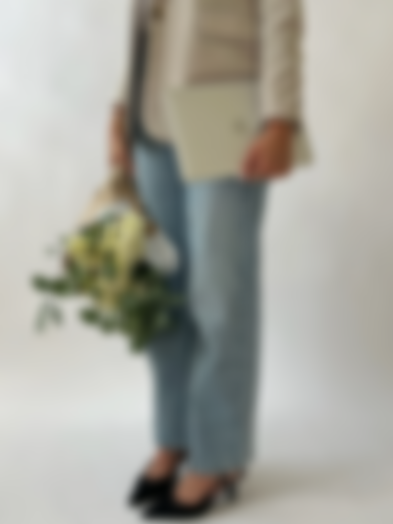 A woman holding a bouquet of white flowers, standing against a plain white background.