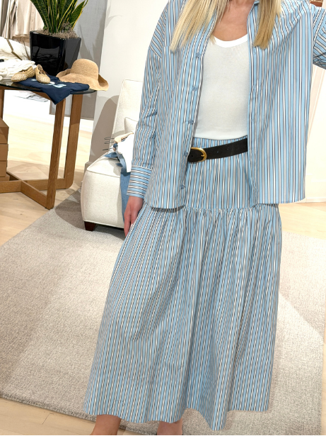 A woman wearing a matching blue and white striped pajama set with a black belt standing in a living room.