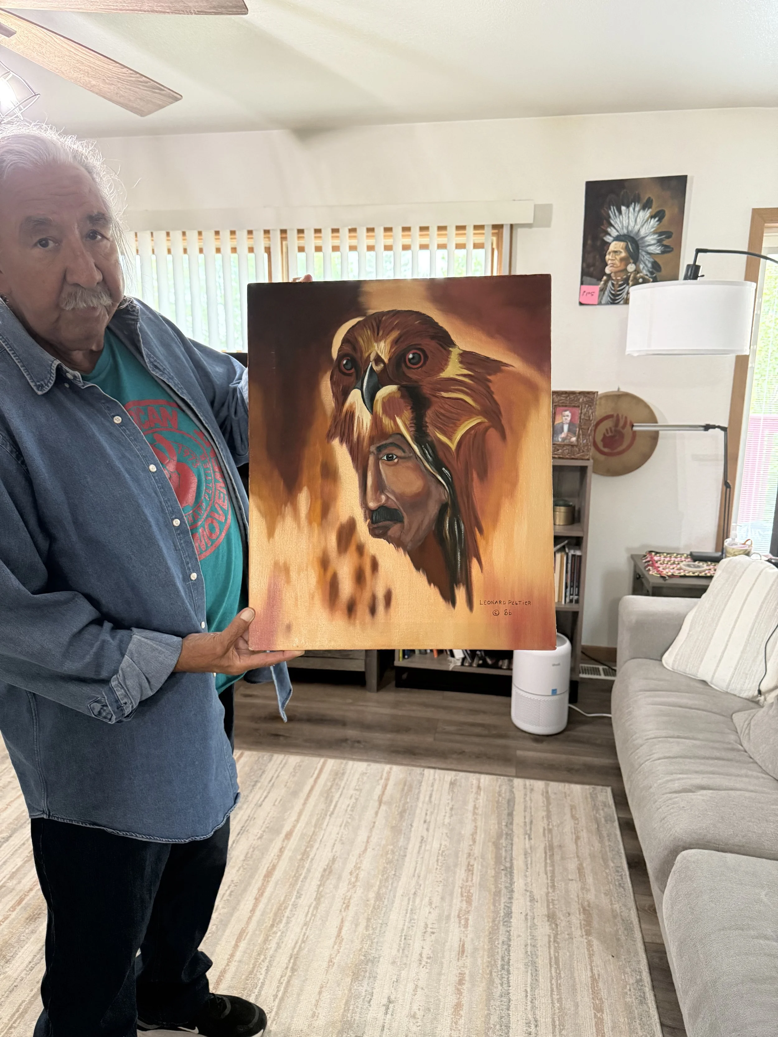 A man holding a painting that depicts a Native American man with an eagle on his head.