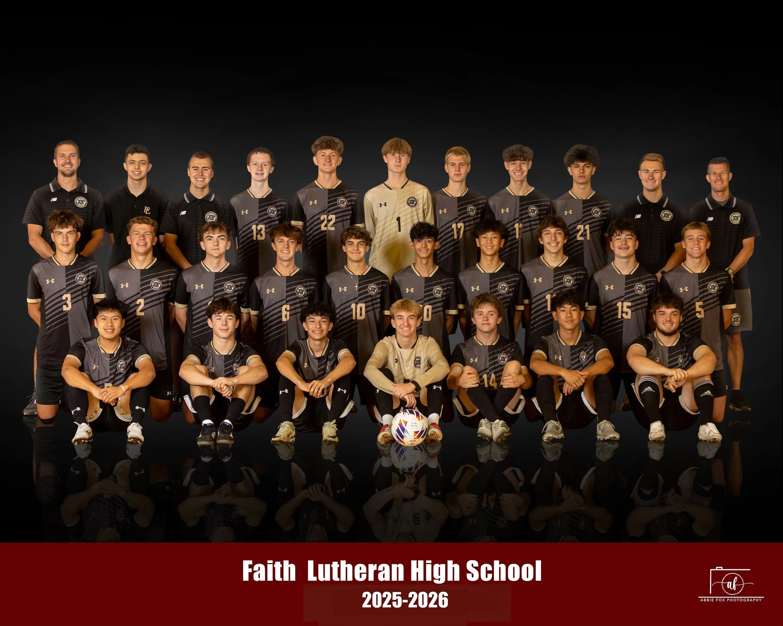 A high school soccer team photo of Faith Lutheran High School, 2025-2026, with players and coaches posing against a dark background. The players are wearing black and gold uniforms, with one in a gold goalkeeper jersey, and the coaches are dressed in black polo shirts. A red banner at the bottom displays the school name and year.