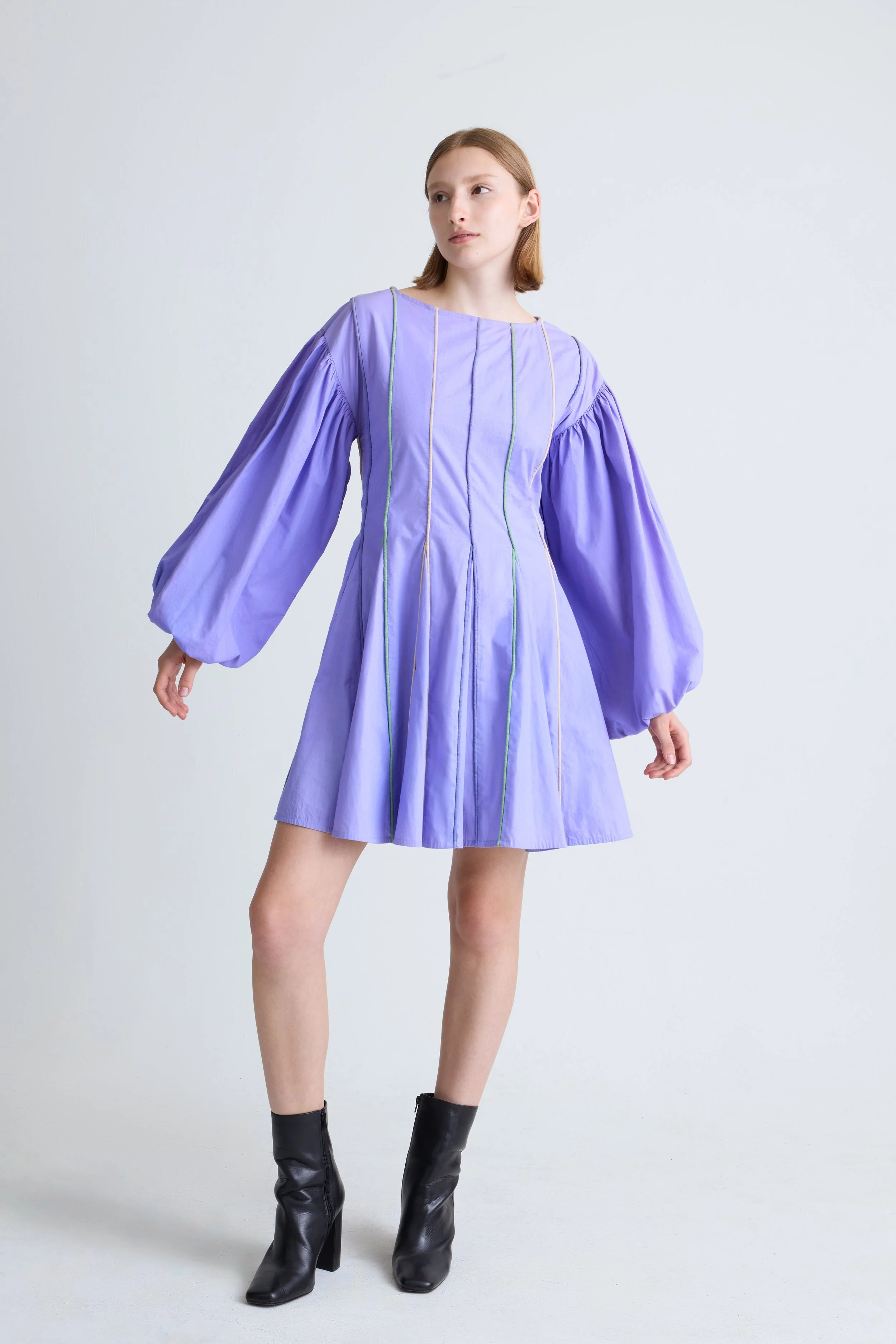 A young woman in a purple dress with puffy long sleeves and black heeled boots