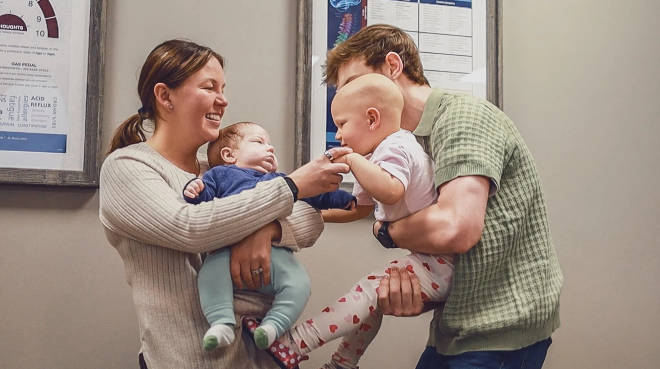 A family joyful reunion with a mother, father, and two children, a baby and a young girl, greeting each other warmly in a chiropractic office Soul Full Chiropractic