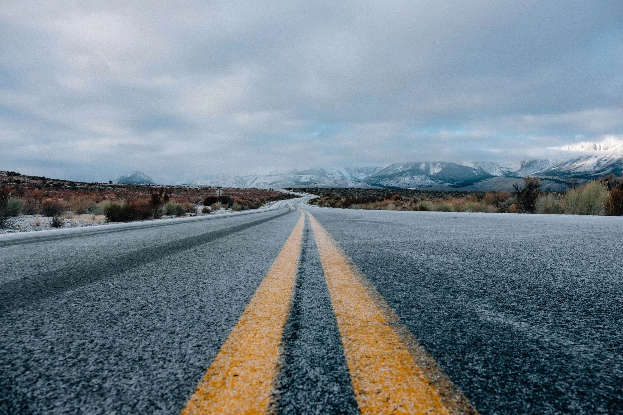 Frost-covered road stretching toward snow-capped mountains executive leadership journey